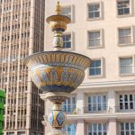 Fonte em espaço público de Porto Alegre, com edifícios urbanos ao fundo, durante o dia
