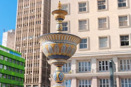 Fonte em espaço público de Porto Alegre, com edifícios urbanos ao fundo, durante o dia