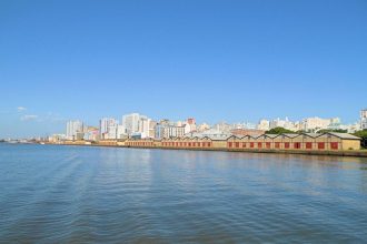 Vista panorâmica da orla de Porto Alegre às margens do Guaíba, com o horizonte da cidade ao fundo.