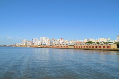 Vista panorâmica da orla de Porto Alegre às margens do Guaíba, com o horizonte da cidade ao fundo.