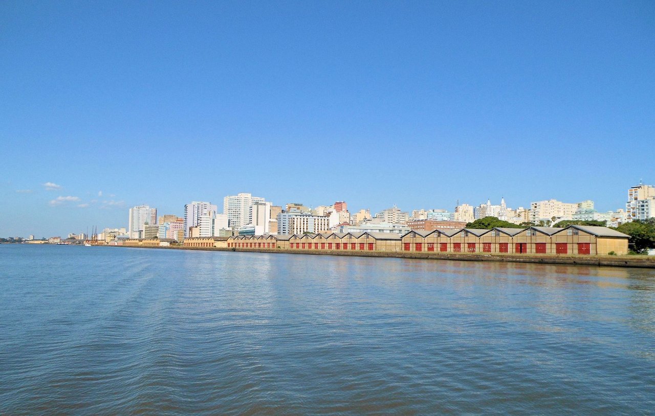 Vista panorâmica da orla de Porto Alegre às margens do Guaíba, com o horizonte da cidade ao fundo.