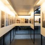 Exposição de artes visuais em galeria contemporânea, com fotografias variadas dispostas nas paredes.