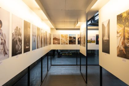 Exposição de artes visuais em galeria contemporânea, com fotografias variadas dispostas nas paredes.